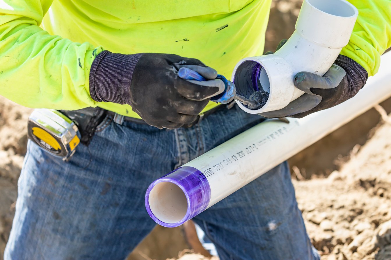 Plumber Applying Pipe Cleaner, Primer and Glue to PVC Pipe at Co